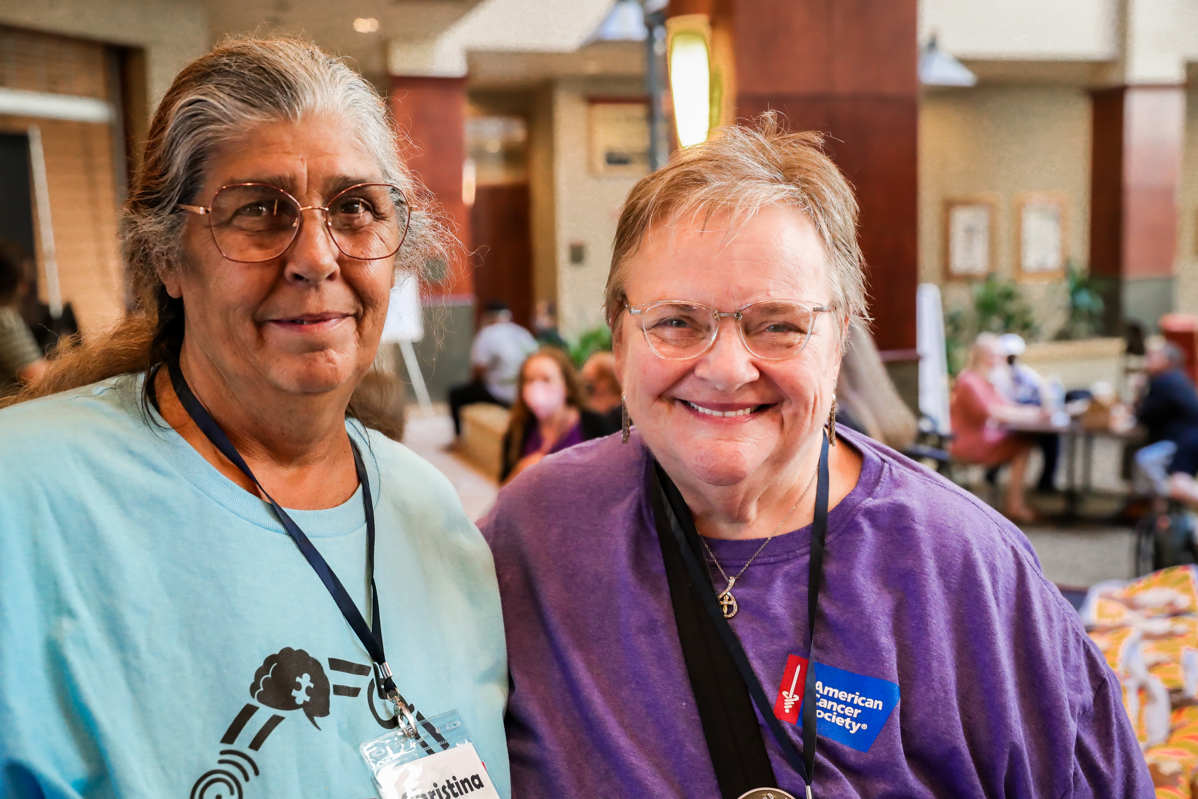 Two female attendees of the Caucus smile as they take a photo together.